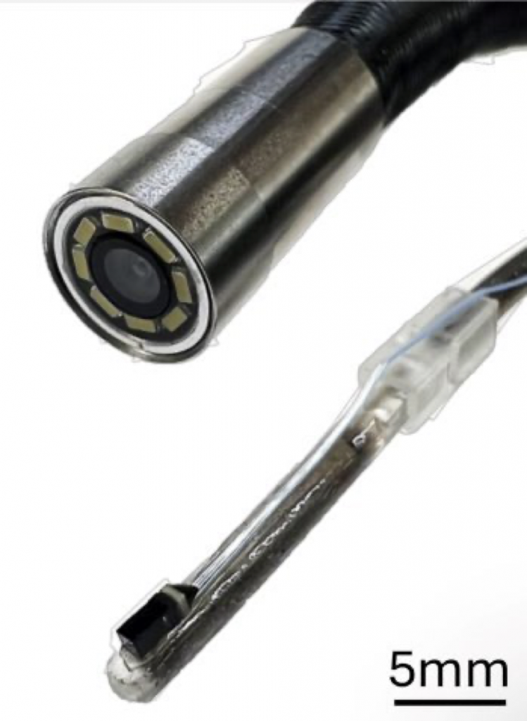 Close-up image of two endeffectors of inspection devices. One is a larger diameter and made of metal with a camera and multiple LEDs in a ring at the tip. The other made of translucent soft polymer much smaller than the rigid one, and with a small camera on the tip.